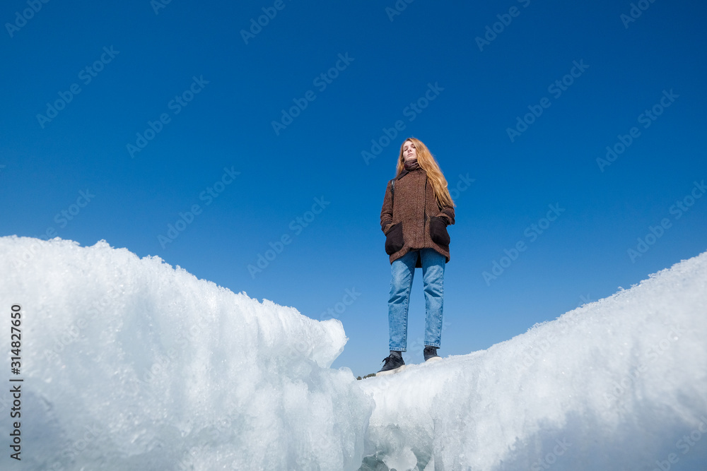 A woman on the background of broken ice covering the lake.