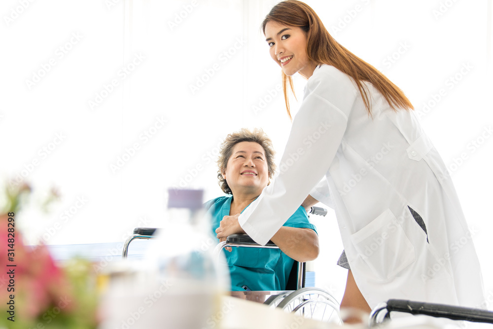 Fototapeta premium Beautiful female doctor Holding the hand of a old female patient at a wheelchair To encourage the sick