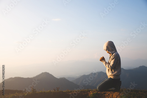 Fototapeta A women is praying to God on the mountain