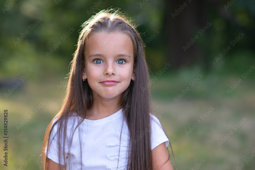 Surprise. Pretty funny little girl with long brown hair posing summer nature outdoor. Cute kid's portrait. Beautiful child's face. Facial expressions. Surprise. Pretty funny little girl with long brown hair posing summer nature outdoor. Cute kid's portrait. Beautiful child's face. Facial expressions.