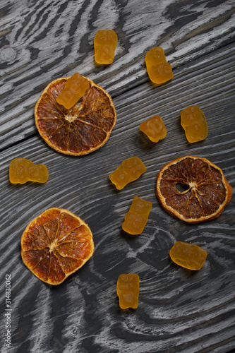 Jelly chewing sweets. Dried slices of orange. Scattered on brushed pine boards painted in black and white.