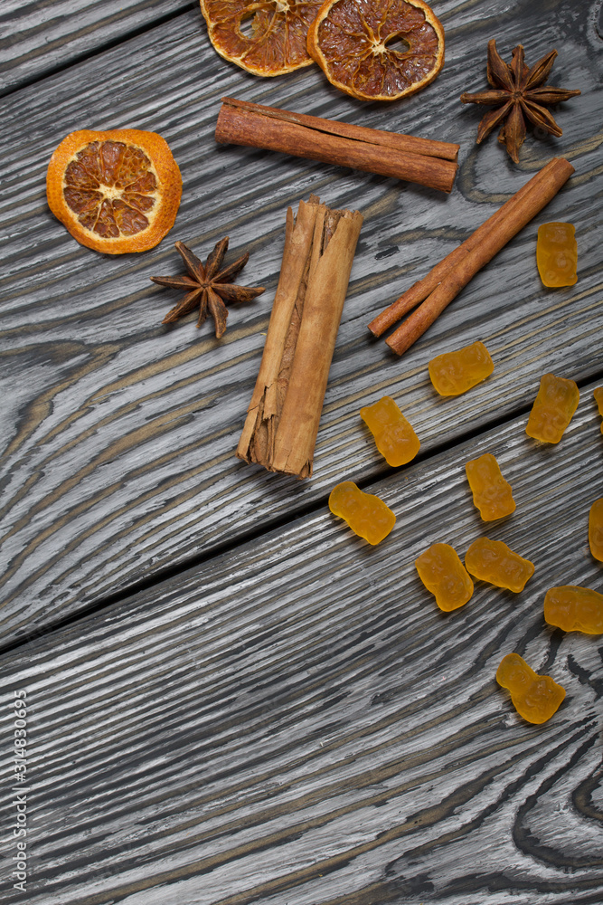 Jelly chewing sweets. Dried slices of orange, cinnamon sticks and anise stars. Scattered on brushed pine boards painted in black and white. Jelly chewing sweets. Dried slices of orange, cinnamon sticks and anise stars. Scattered on brushed pine boards painted in black and white.