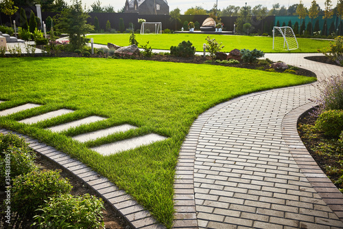 Landscaping of the garden. path curving through Lawn with green grass and walkway tiles. photo