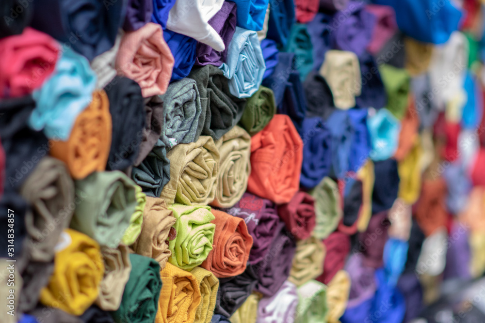 Rolls of vibrant colorful tshirts stacked in a store, comfortable seasonal clothing