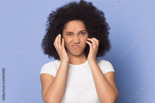 Irritated african american millennial lady suffering from unpleasant sound.