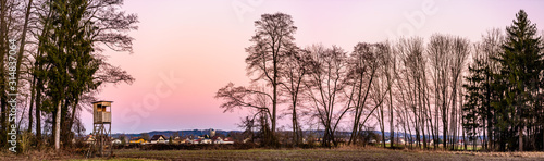 Panorama landscape with hunting tower after sunset in rural scenery against pink sky. Deer stand near Zettling Graz in Austria. Hunting concept