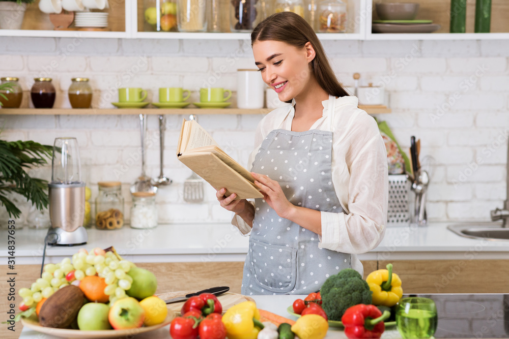 Girl reading cookbook in the kitchen, looking for recipe Girl reading cookbook in the kitchen, looking for recipe