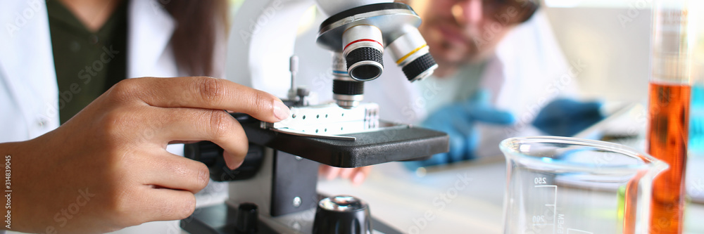 Two scientists of a student chemist are conducting research using microscope for bacterial contamination of water to search for vaccine to treat diseases in medicine Two scientists of a student chemist are conducting research using microscope for bacterial contamination of water to search for vaccine to treat diseases in medicine