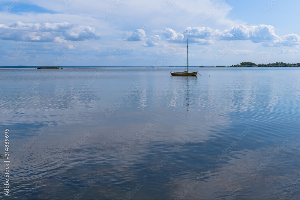Seascape. An empty boat with a mast is anchored in the sea bay on a summer day. Seascape. An empty boat with a mast is anchored in the sea bay on a summer day.