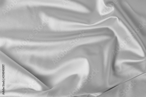 Gray silk background with a folds. Abstract texture of rippled satin surface