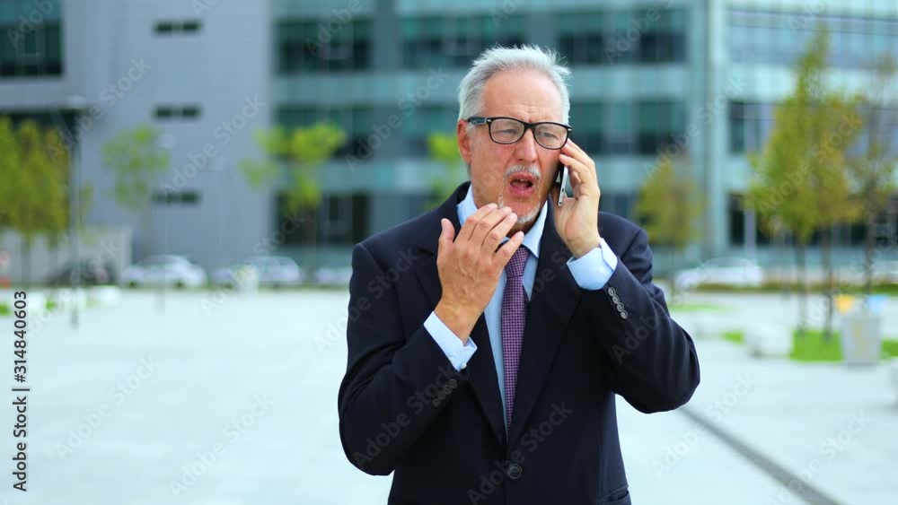 Senior manager on the phone while walking in a modern city Senior manager on the phone while walking in a modern city