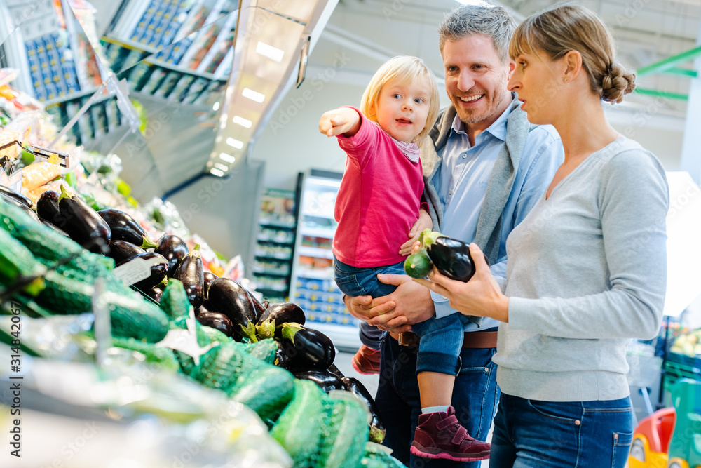 Obraz premium Family with little child having fun buying produce in supermarket