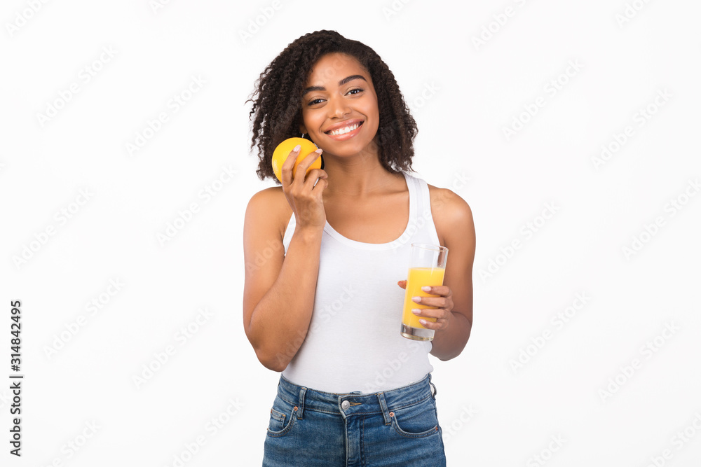Smiling afro girl drinking orange juice holding fruit Smiling afro girl drinking orange juice holding fruit