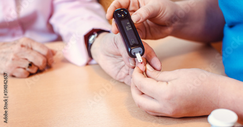 Nurse administers diabetes test to senior in nursing home © Kzenon