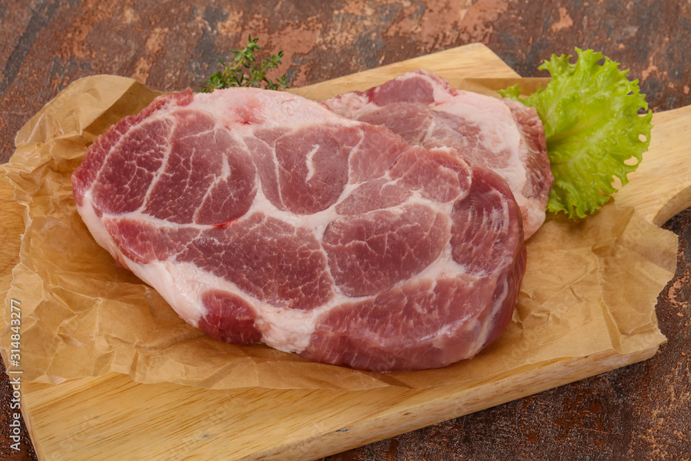 Raw pork steak over wooden board