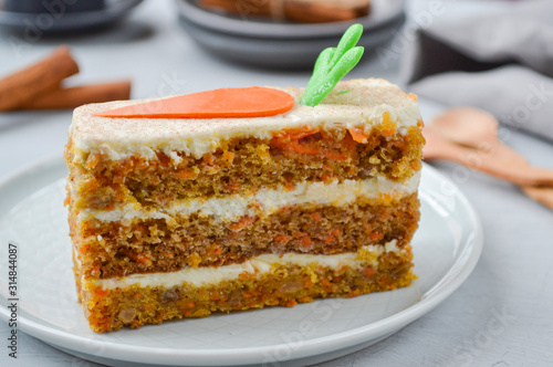 National Carrot Cake Day.  Carrot cake with cream cheese frosting decorated with chocolate carrots on a light wooden background. Close-up, top view