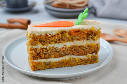 Carrot Cake Day.  Carrot cake with cream cheese frosting decorated with chocolate carrots on a light wooden background. Close-up, top view