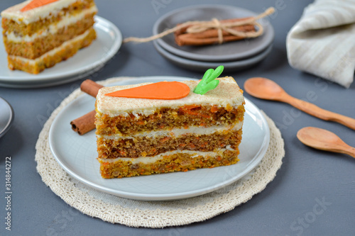 National Carrot Cake Day.  Carrot cake with cream cheese frosting decorated with chocolate carrots on a gray wooden background. Close-up, top view