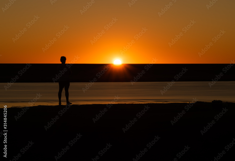 Silhouette of man watching the sunset on a riverbed in Australia