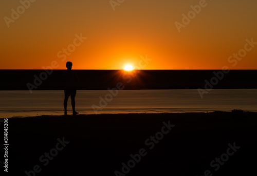 Silhouette of man watching the sunset on a riverbed in Australia © Jacob
