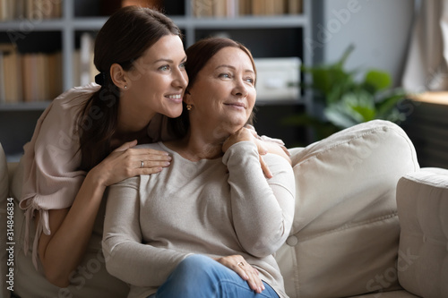 Foto Smiling middle-aged mum and adult daughter dreaming together