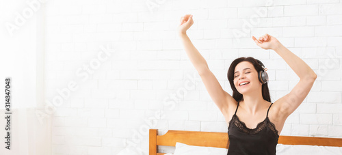 Happy girl dancing in headphones, waking up in morning