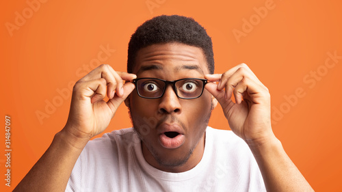 Surprised african american guy touching his eyewear photo