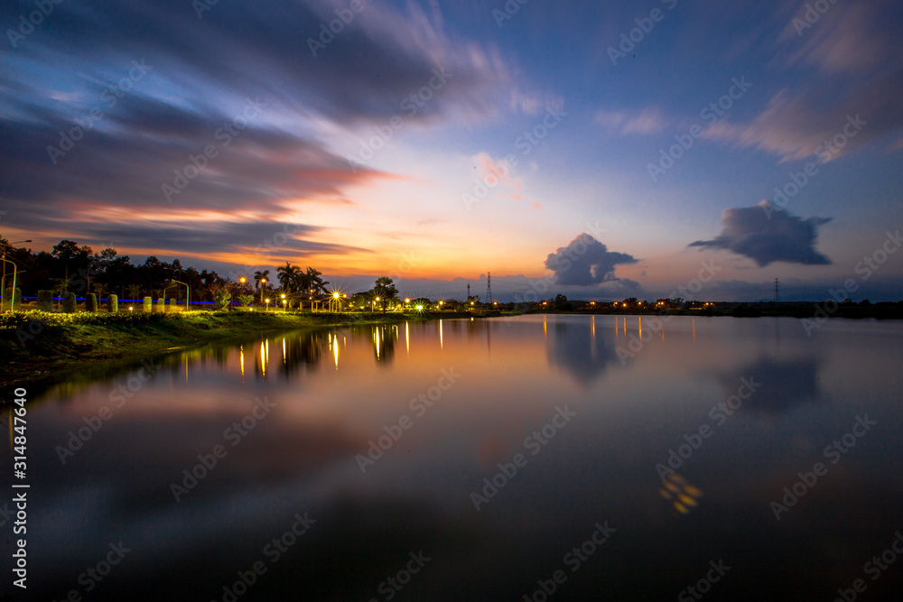 The blurred abstract background of the colorful twilight evening sky near the large lake, with cool breezes while sitting or exercising in the park.