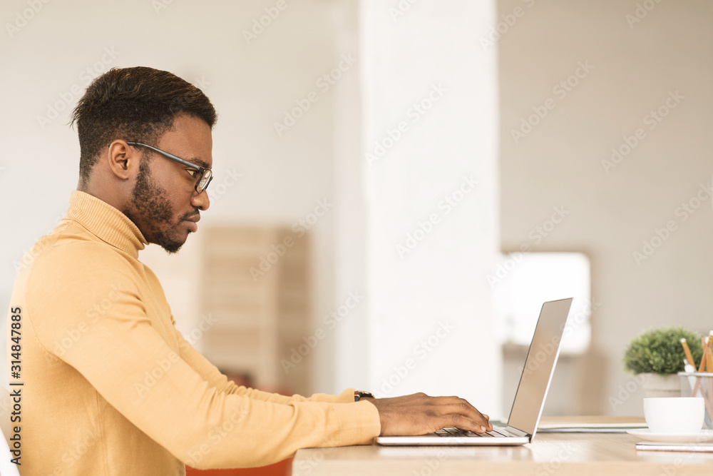 Afro guy working on his laptop at home - obrazy, fototapety, plakaty 