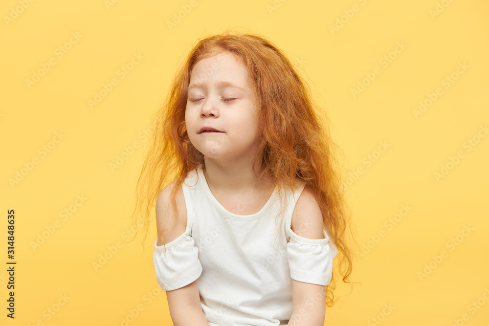 Pretty little girl in stylish summer top playing hide and seek, couting to ten, keeping eyes closed. Beautiful redhead female child practicing meditaiton. Mindfulness, balance and peace concept Pretty little girl in stylish summer top playing hide and seek, couting to ten, keeping eyes closed. Beautiful redhead female child practicing meditaiton. Mindfulness, balance and peace concept