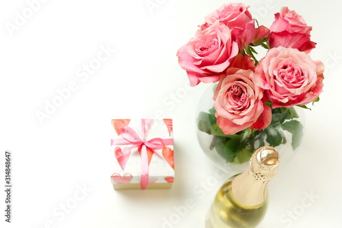 Valentine's day background. Bouquet of pink roses flowers, gift box and champagne bottle isolated on white background with copy space. Top view flat lay