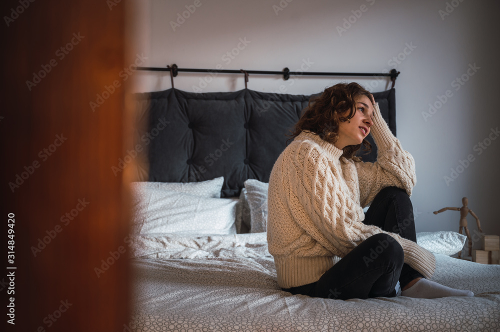 Obraz premium Young woman sitting in bed relaxed, smiling and enjoying the morning