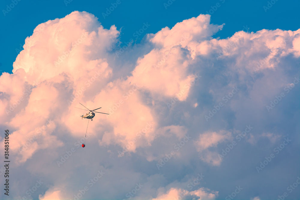 Helicopter with bucket full of water in a sky Helicopter with bucket full of water in a sky