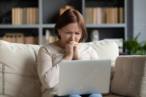 Fotografia Upset senior woman read bad news on laptop at home