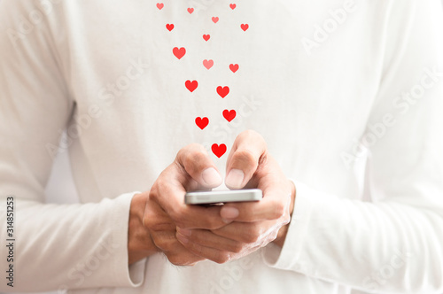 Hand pushing red hearts icon with smartphone for Valentine day concept