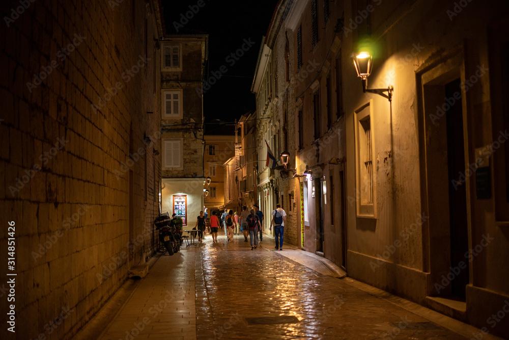 A street at night in Zadar old town in Chroatia with people walking and lanterns / night lights