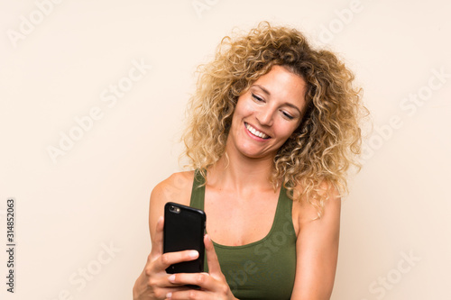 Young blonde woman with curly hair using mobile phone