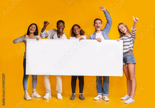 Happy smiling group of students standing together with white placard