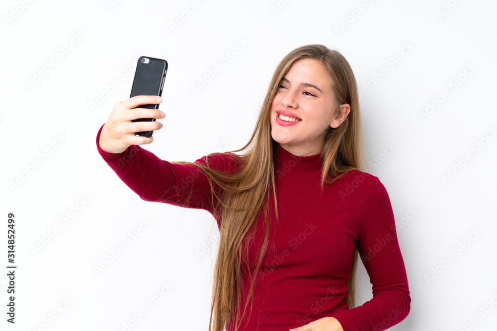 Teenager blonde girl over isolated white background making a selfie Teenager blonde girl over isolated white background making a selfie