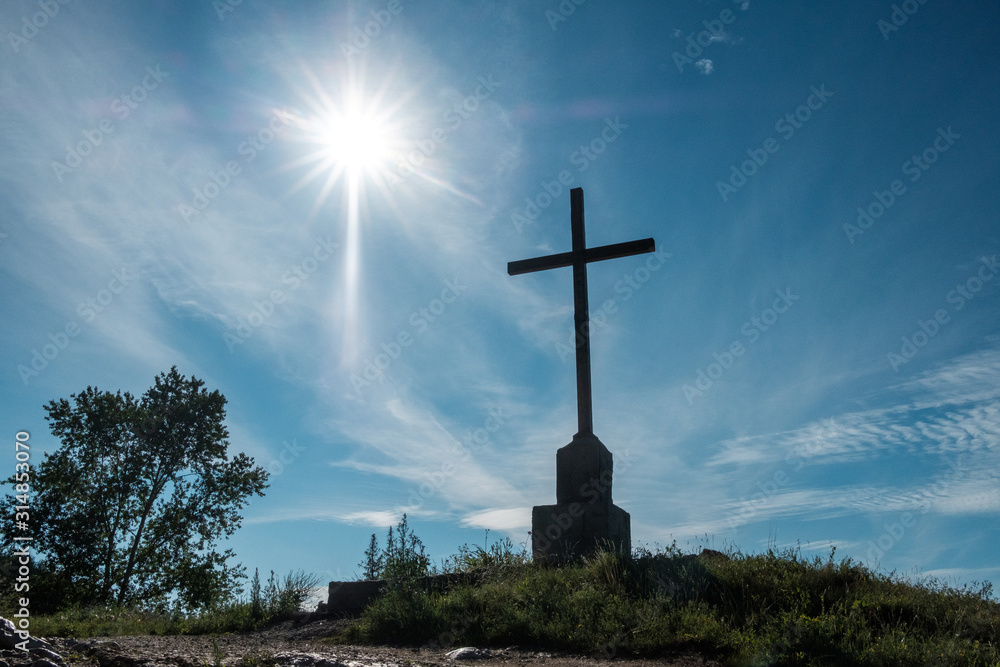 cross on a mountain against a blue sky and bright sun cross on a mountain against a blue sky and bright sun