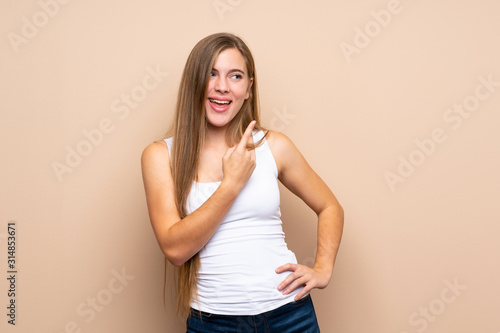 Teenager blonde girl over isolated background pointing to the side to present a product