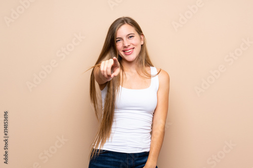 Teenager blonde girl over isolated background points finger at you with a confident expression