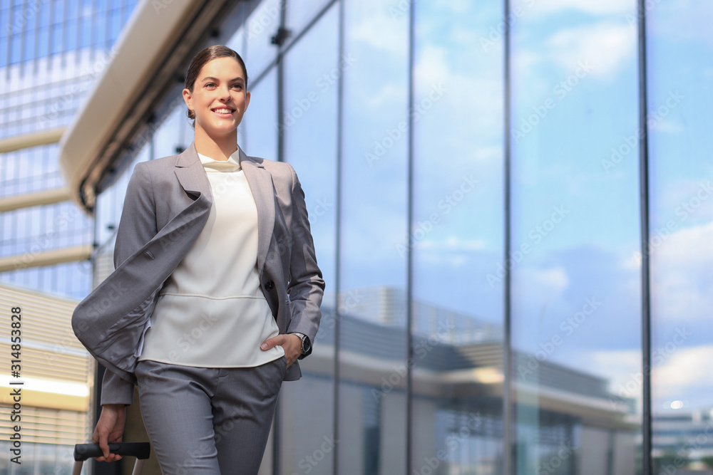 Portrait of successful business woman in suit looking away while walking outdoors.
