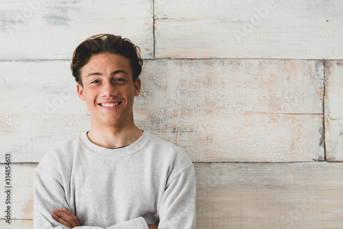 one teenager at home smiling happy at the camera - simple photo of handsome young man looking with wooden wall at the background photo