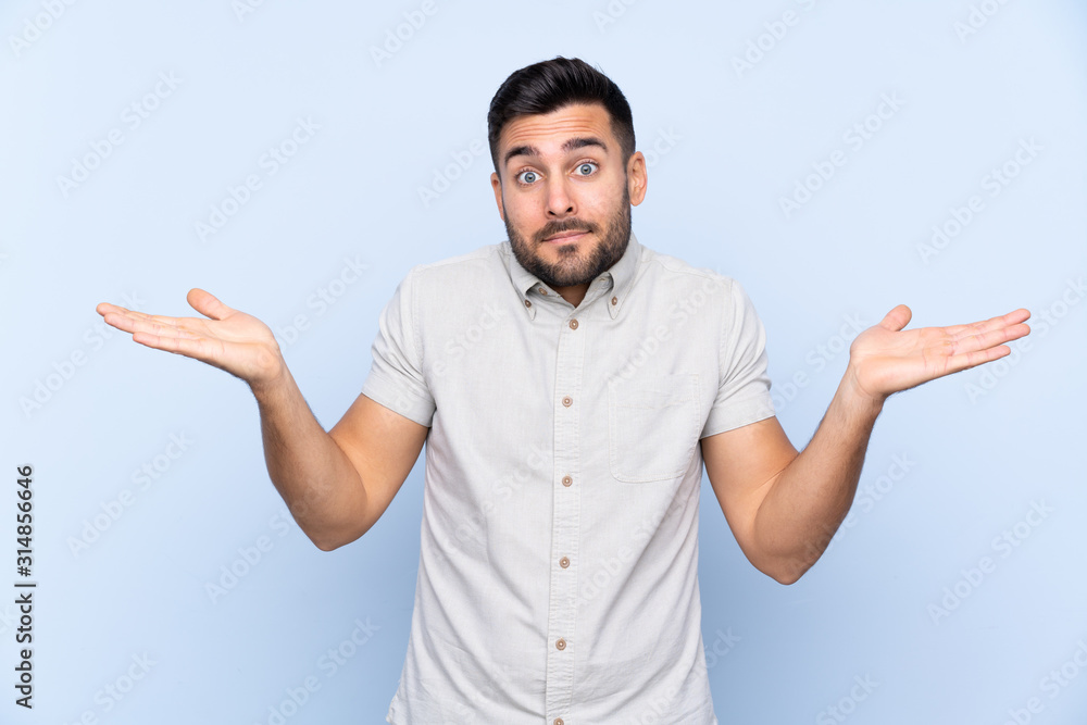 Fototapeta premium Young handsome man with beard over isolated blue background having doubts with confuse face expression