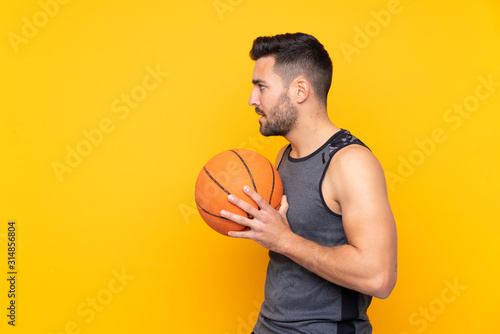 Man over isolated yellow background playing basketball