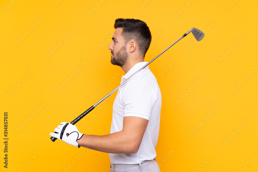Man over isolated yellow background playing golf Man over isolated yellow background playing golf