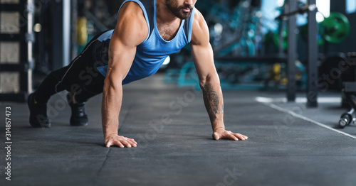 Sportsman making plank or push ups exercise at gym