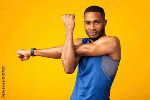 Healthy black guy stretching hand and shoulder before workout