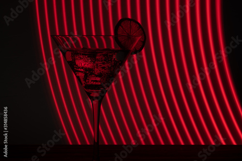 Glass of martini with ice shot in a long exposure in neon light